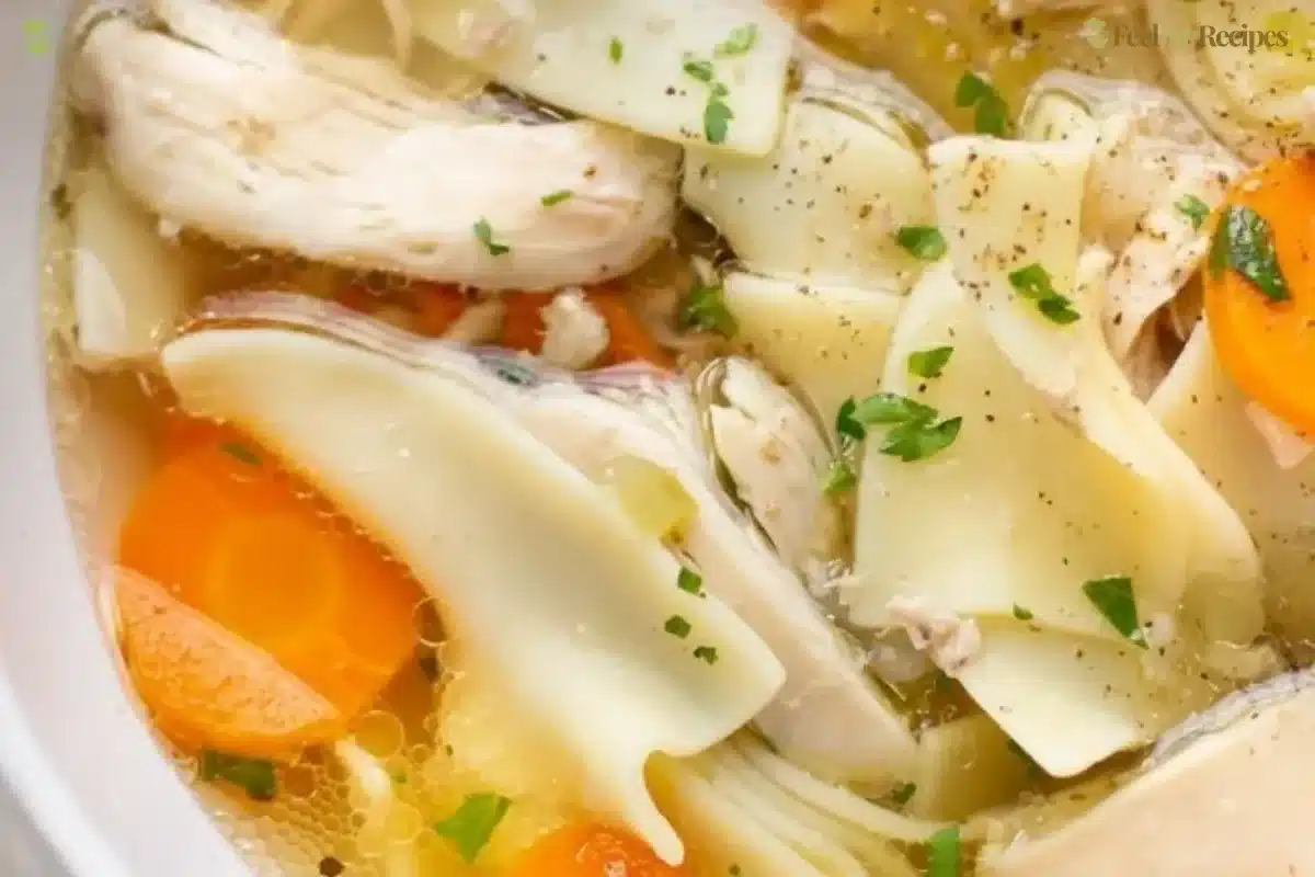 Bowl of classic chicken noodle soup with carrots and noodles on a table