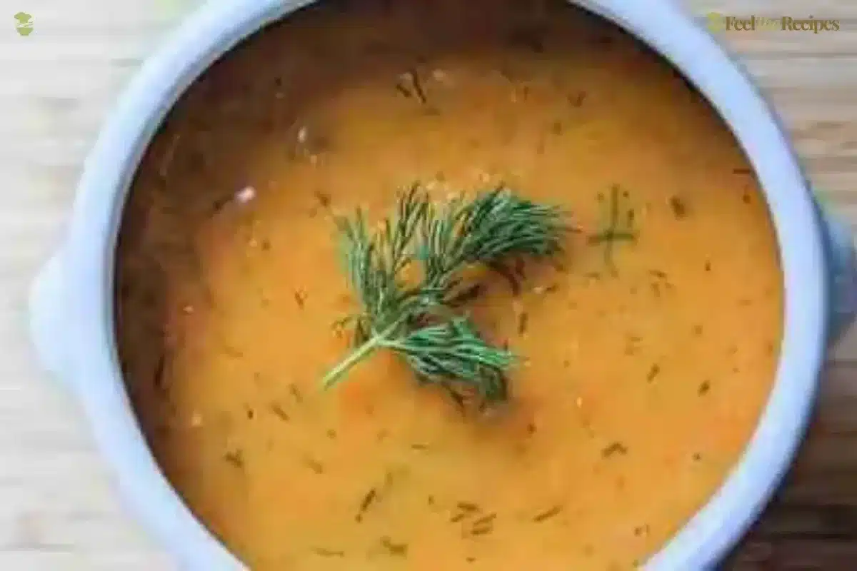 Bowl of lemony carrot soup garnished with dill and a slice of lemon