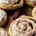 Freshly baked cinnamon roll cookies topped with icing and cinnamon.