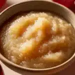 Bowl of homemade unsweetened applesauce prepared with fresh apples.