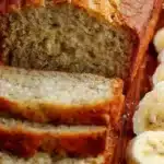 Slice of easy moist banana bread with ripe bananas and nuts on a wooden table