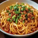 Bowl of effortless Szechuan noodles topped with fresh vegetables and herbs