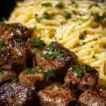 Garlic Butter Steak Bites served with creamy parmesan pasta on a plate.