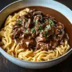 Slow Cooker Beef & Noodles dish served in a white bowl with herbs
