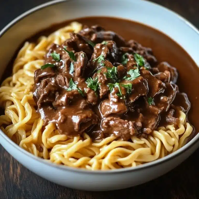 Slow Cooker Beef & Noodles dish served in a white bowl with herbs