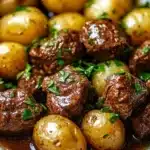 Slow Cooker Garlic Butter Beef Bites served with potatoes in a rustic setting