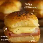 Ham and Havarti Cheese Sliders on a platter, garnished with herbs.