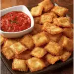 Plate of crispy toasted ravioli bites served with marinara sauce