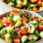 A bowl of Classic Italian Cucumber Salad garnished with herbs and spices.