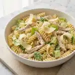 High-Protein Chicken Caesar Pasta Salad in a bowl garnished with parmesan