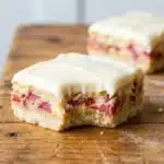 Delicious rhubarb custard bars served on a plate with fresh rhubarb
