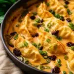 Viral Dumpling Bake with creamy red curry sauce in a one-pan dish, garnished with herbs.